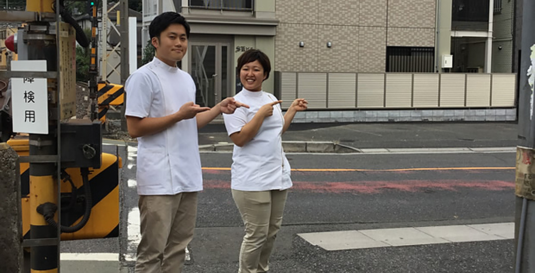 踏切前の交差点で右に曲がる地点をご案内するスタッフ