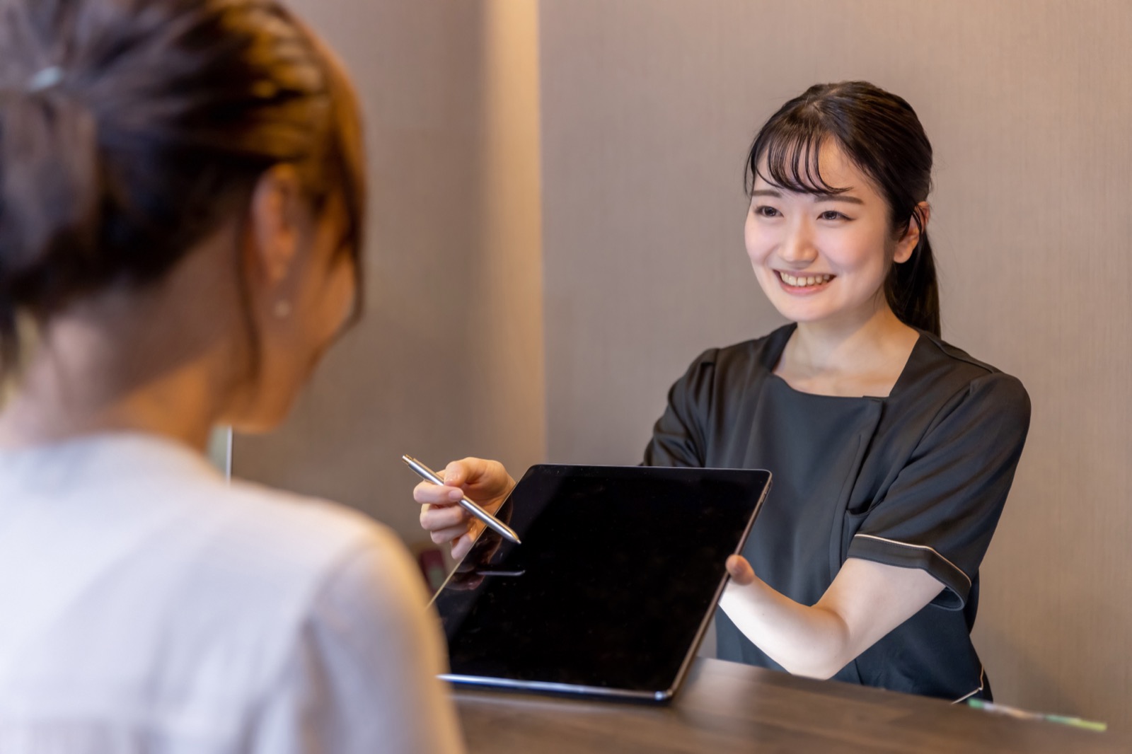 施術着のスタッフがタブレットを見せて説明する様子