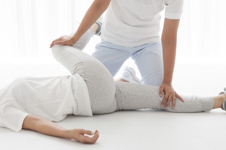 横向きに寝た状態で膝を倒して骨盤を動かす施術