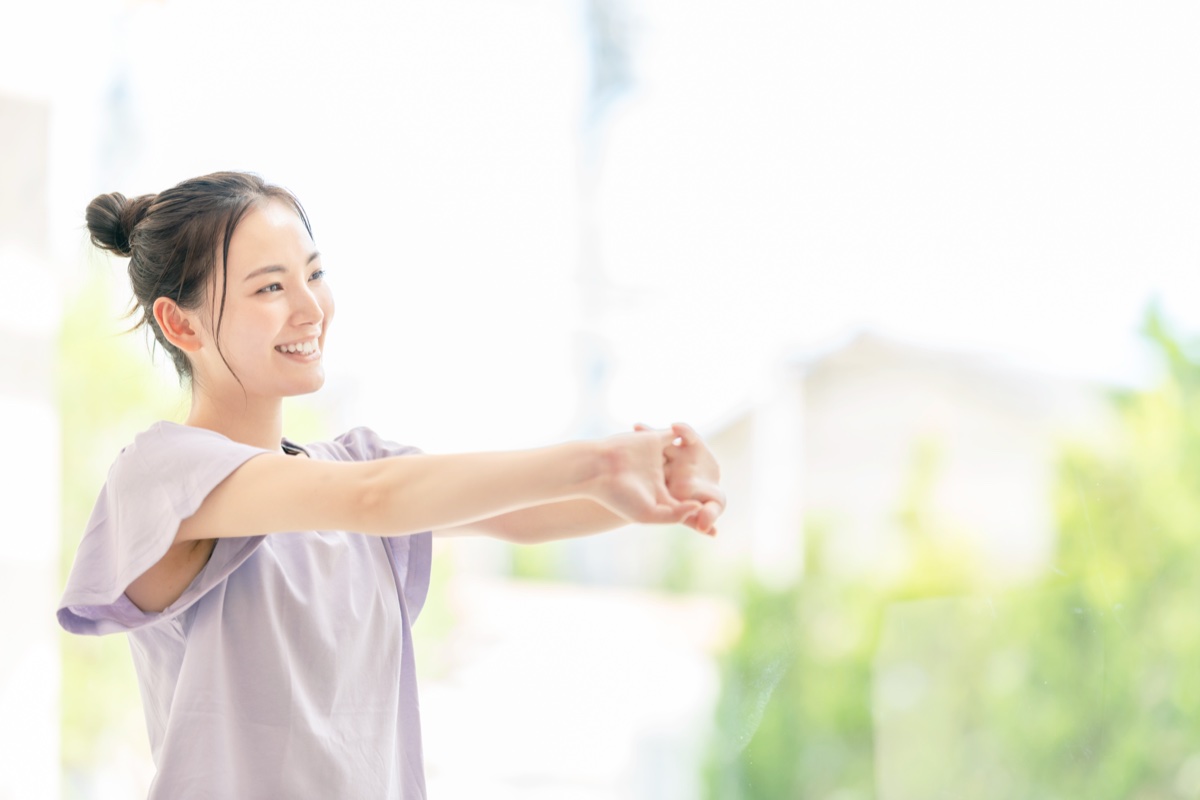 胸の前で両手を組み、腕をまっすぐ前に伸ばす女性