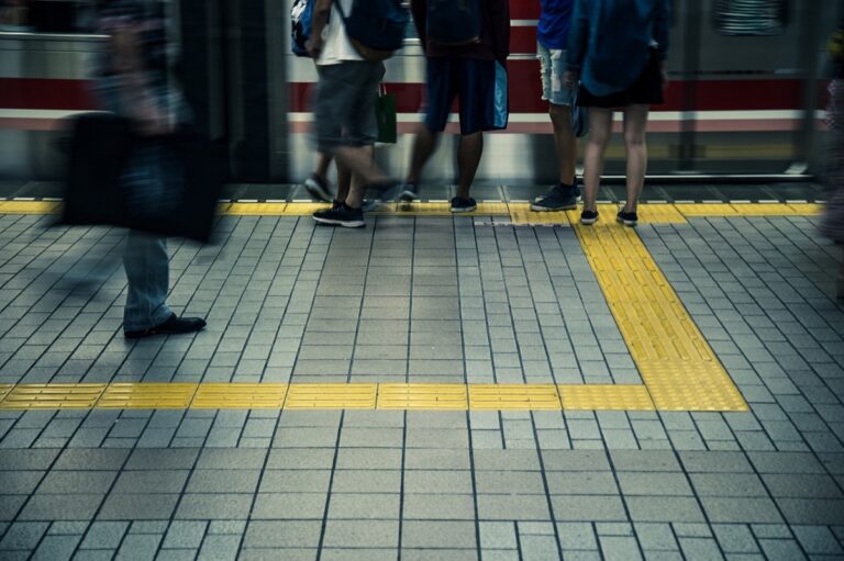 駅のホームで電車を待つ人々と黄色い点字ブロック